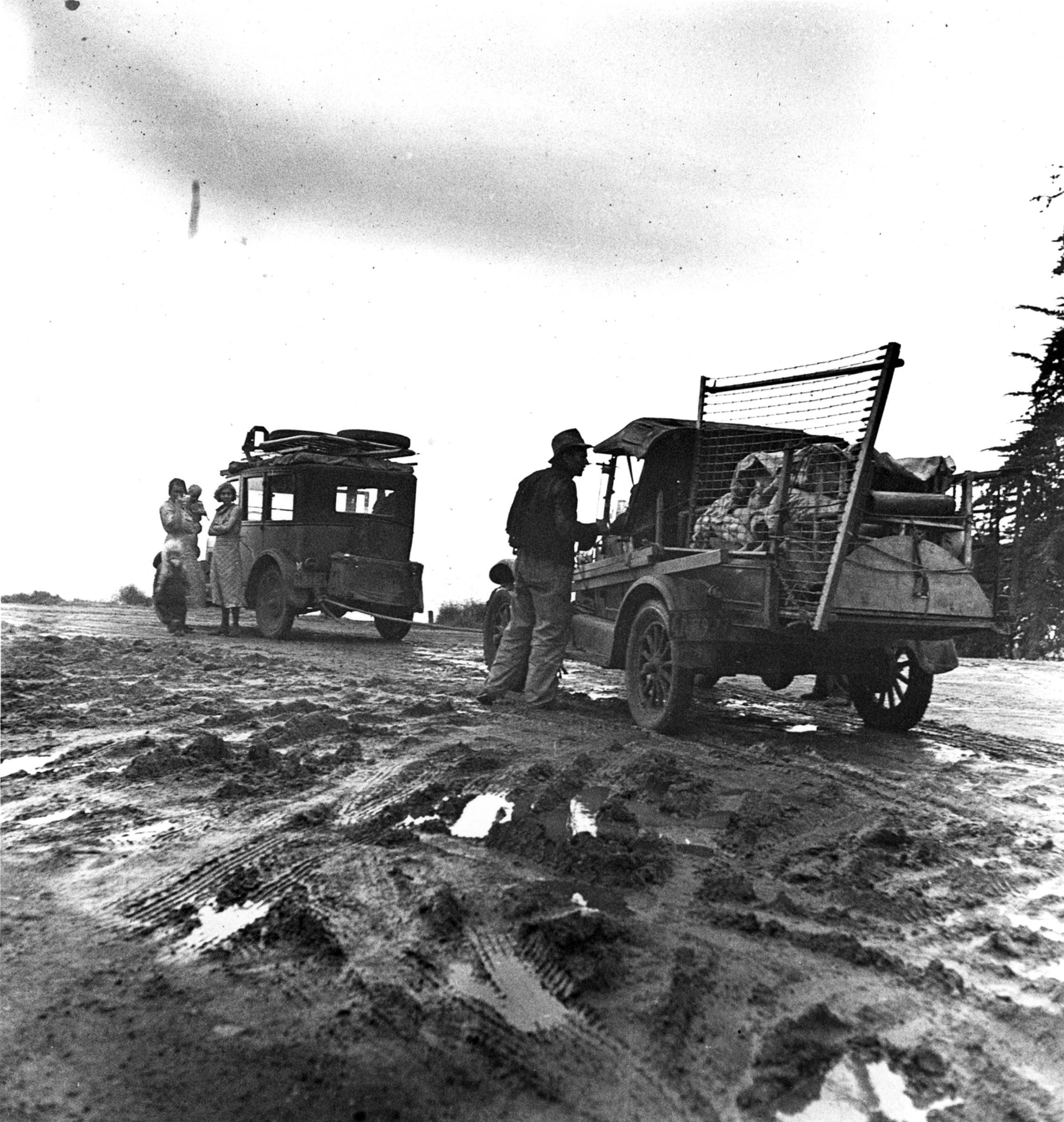 Their worldly possessions piled on two rundown vehicles, this migrant family paused en route to California in February 1936.