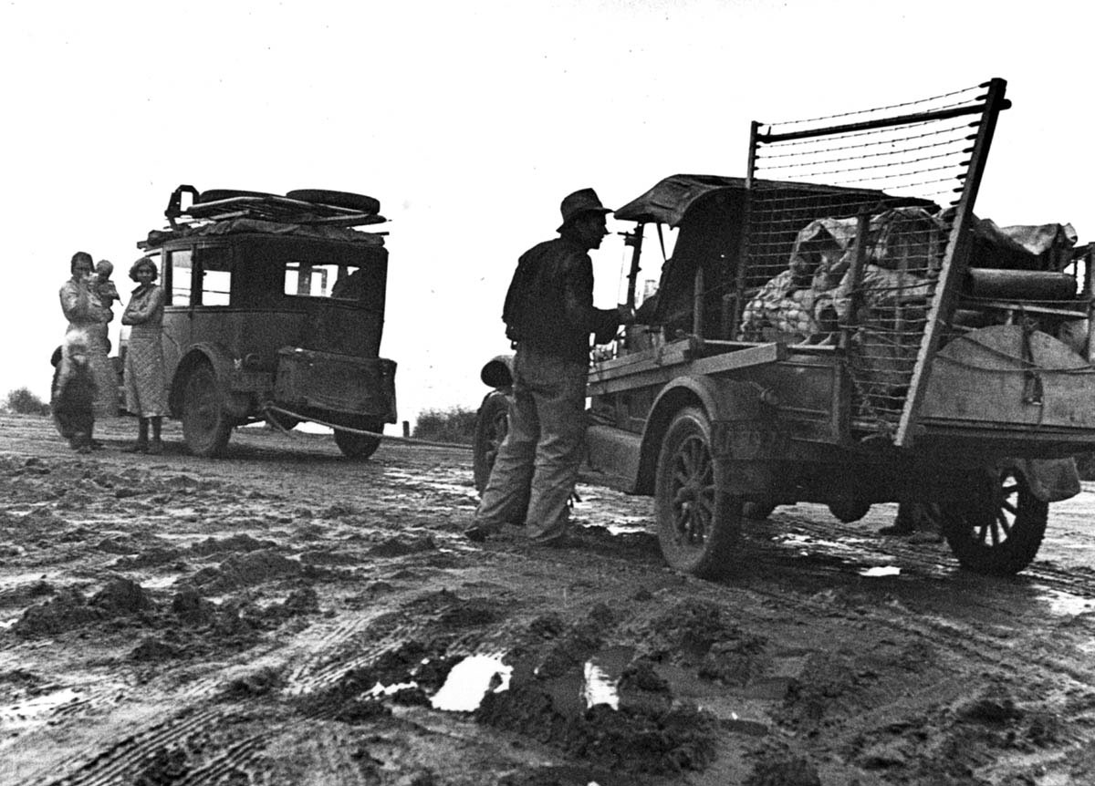 Their worldly possessions piled on two rundown vehicles, this migrant family paused en route to California in February 1936.