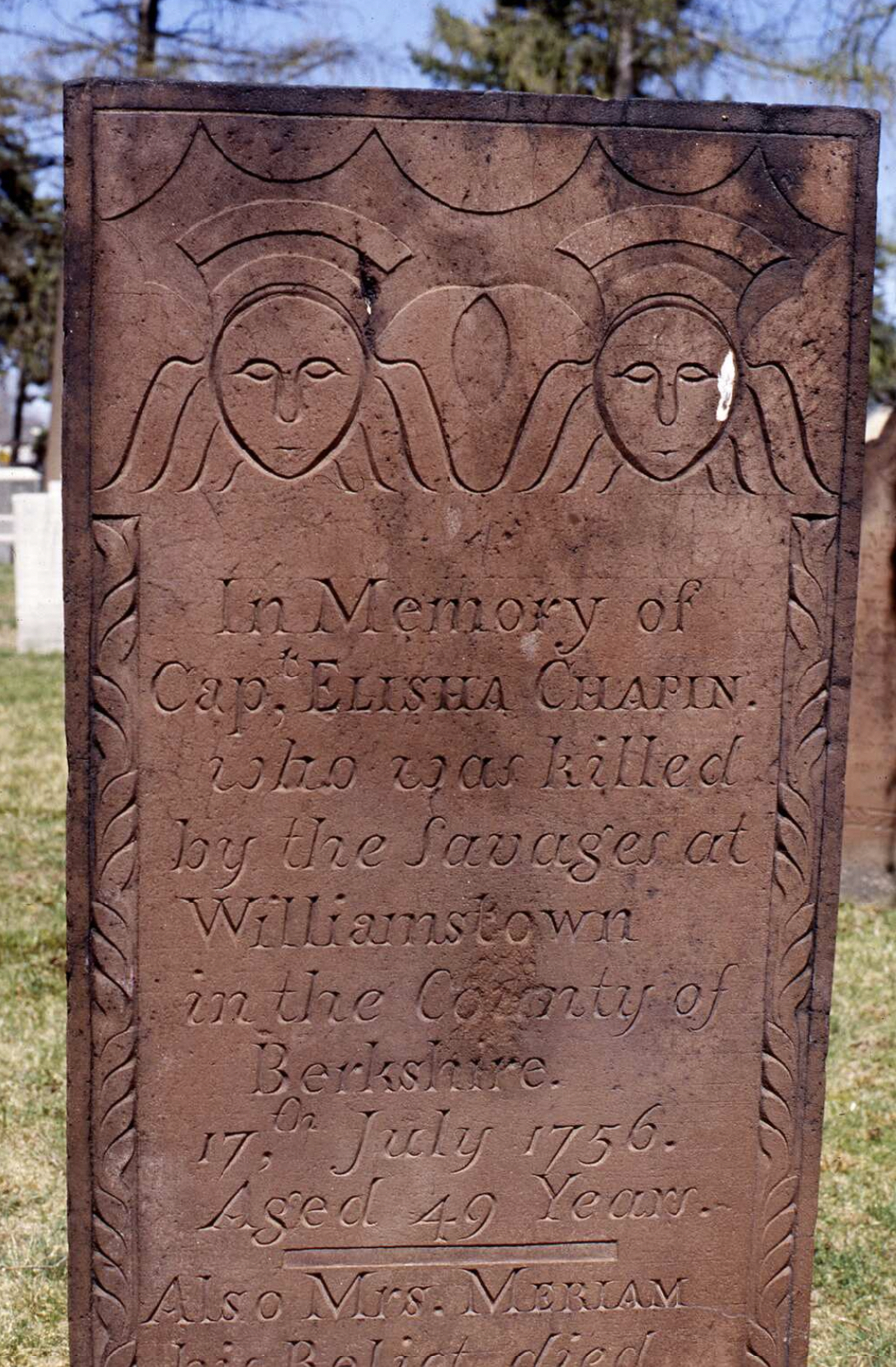 This gravestone marks the deaths of Elisha and Meriam Chapin, of Springfield, Massachusetts. The stone reads: “In Memory of Cap. Elisha Chapin who was killed by the savages at Williamstown in the County of Berkshire, 17th July 1756. Aged 49 Years. Also Mrs. Meriam his relict died 6th October 1800, Aged 83 Years.” The epitaph and the bottom of the stone are cut off in the original image.