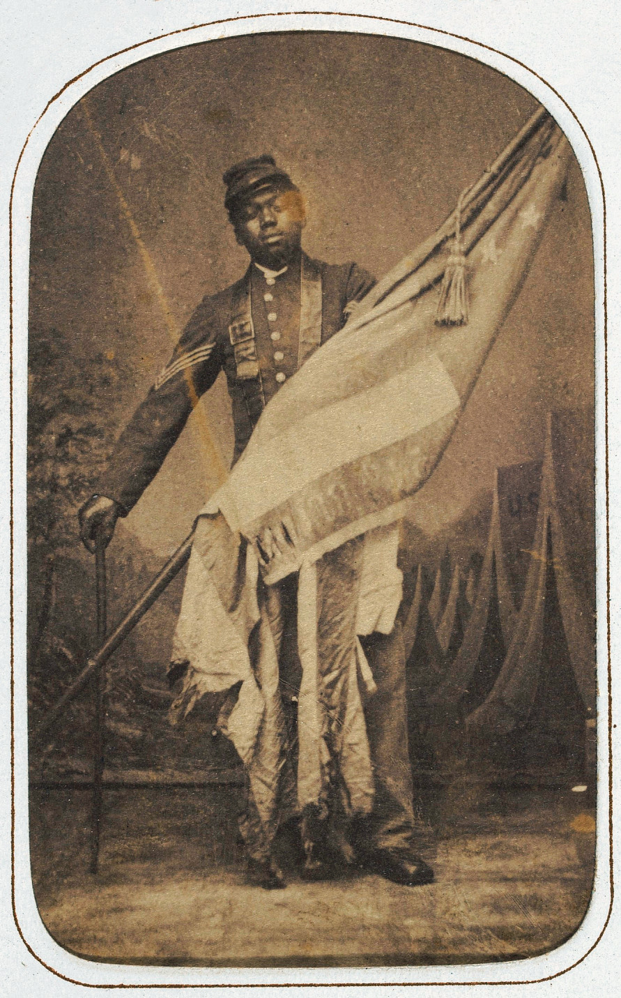 The carte-de-visite photograph of William H. Carney holding the Stars and Stripes operates as a commemorative portrait. Initially denied the right to serve, Black Civil War soldiers fought gallantly on the war front while facing continued discrimination on the home front. This portrait of Carney celebrates his courage in securing and raising the American flag during battle.