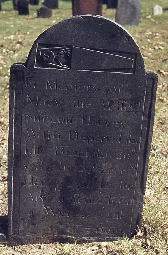 This gravestone marks the death of Mary Simeon of Deerfield, Massachusetts. The stone reads: “In memory of Mary, the wife of Simeon Harvey Who Departed This Life December 20 1785, in the 39th year of Her age, on her left Arm lieth the Infant Which was still born.”