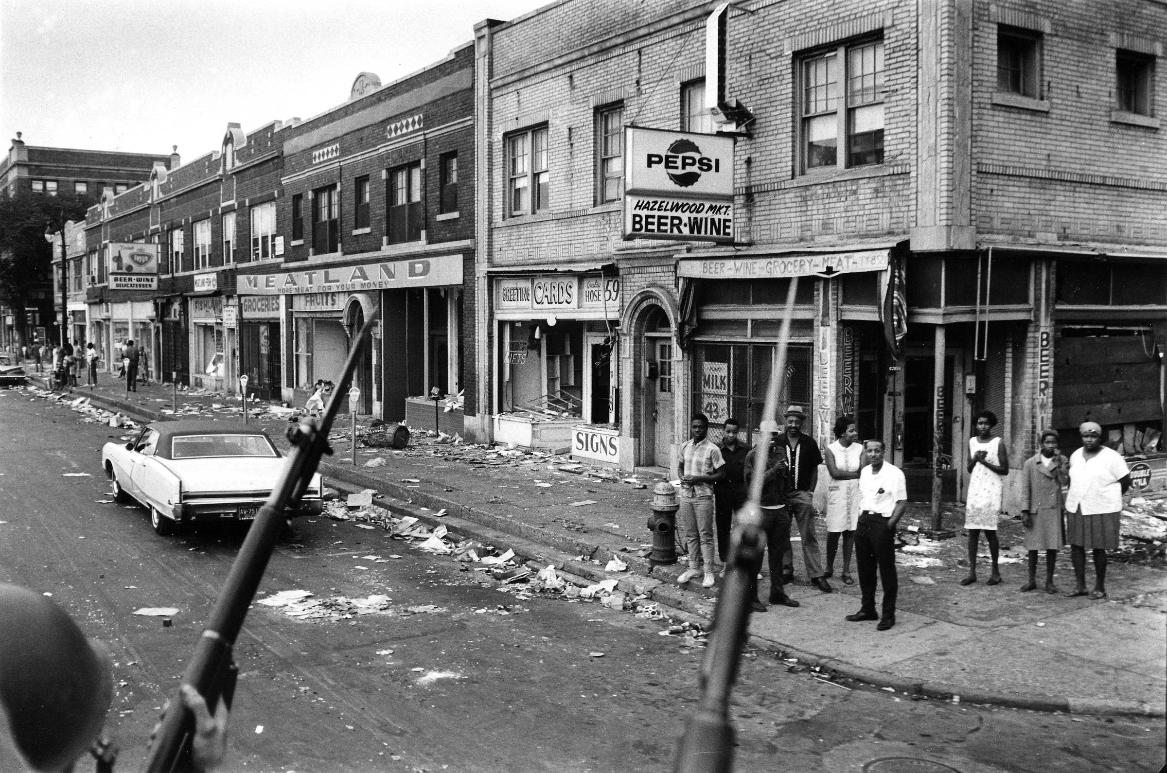 African American residents gaze at a National Guard patrol on the second day of the 1967 Detroit riot.