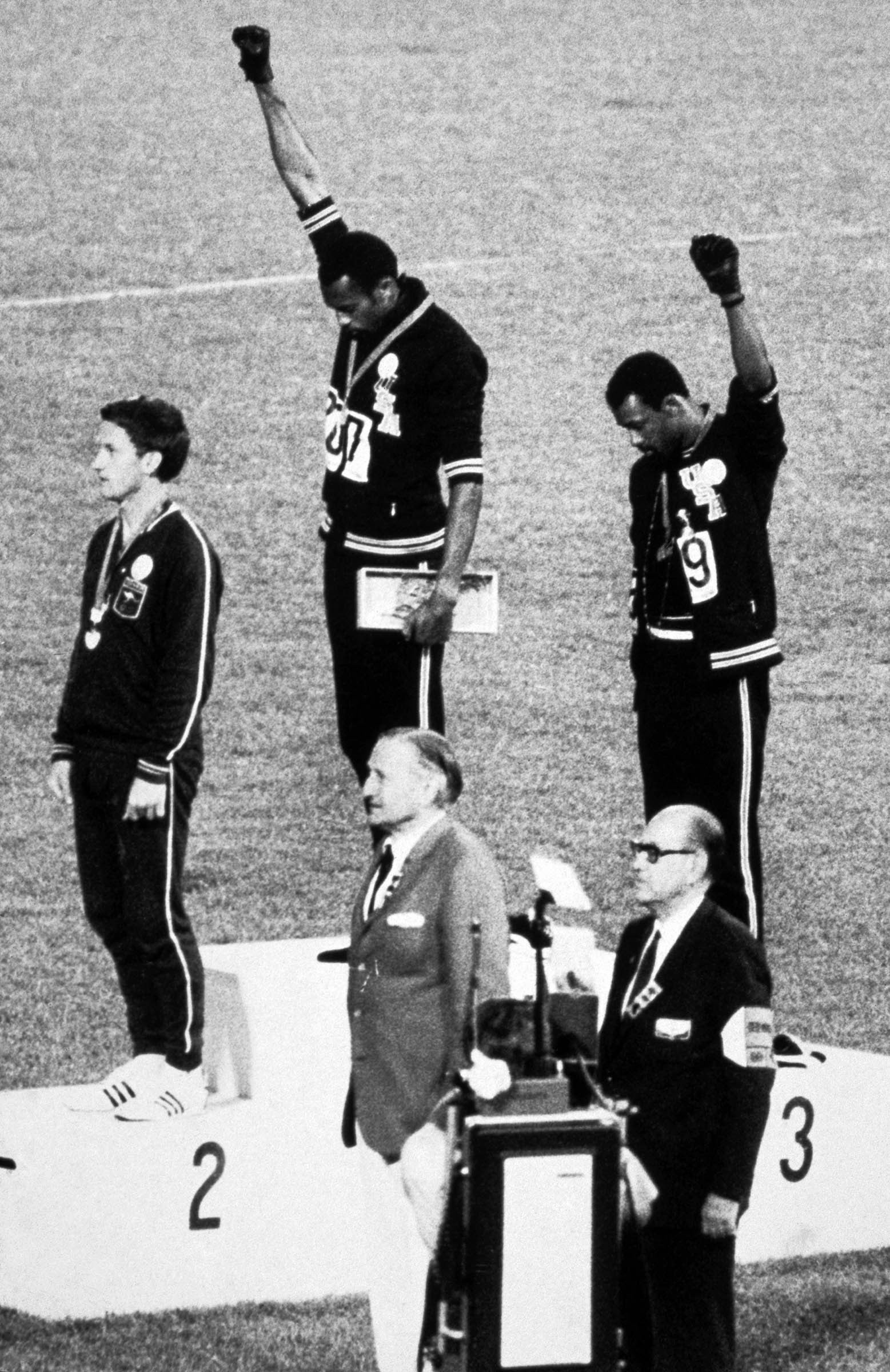 As <em>The Star-Spangled Banner</em> is played during the 1968 Mexico City Olympics, the American gold and bronze medalists in the 200-meter dash raise their fists in the Black Power salute. Outraged by this silent tribute to Black dignity and protest against racial discrimination in sports, the International Olympics Committee ejected Tommie Smith (center) and John Carlos (right) from the Olympic Village.