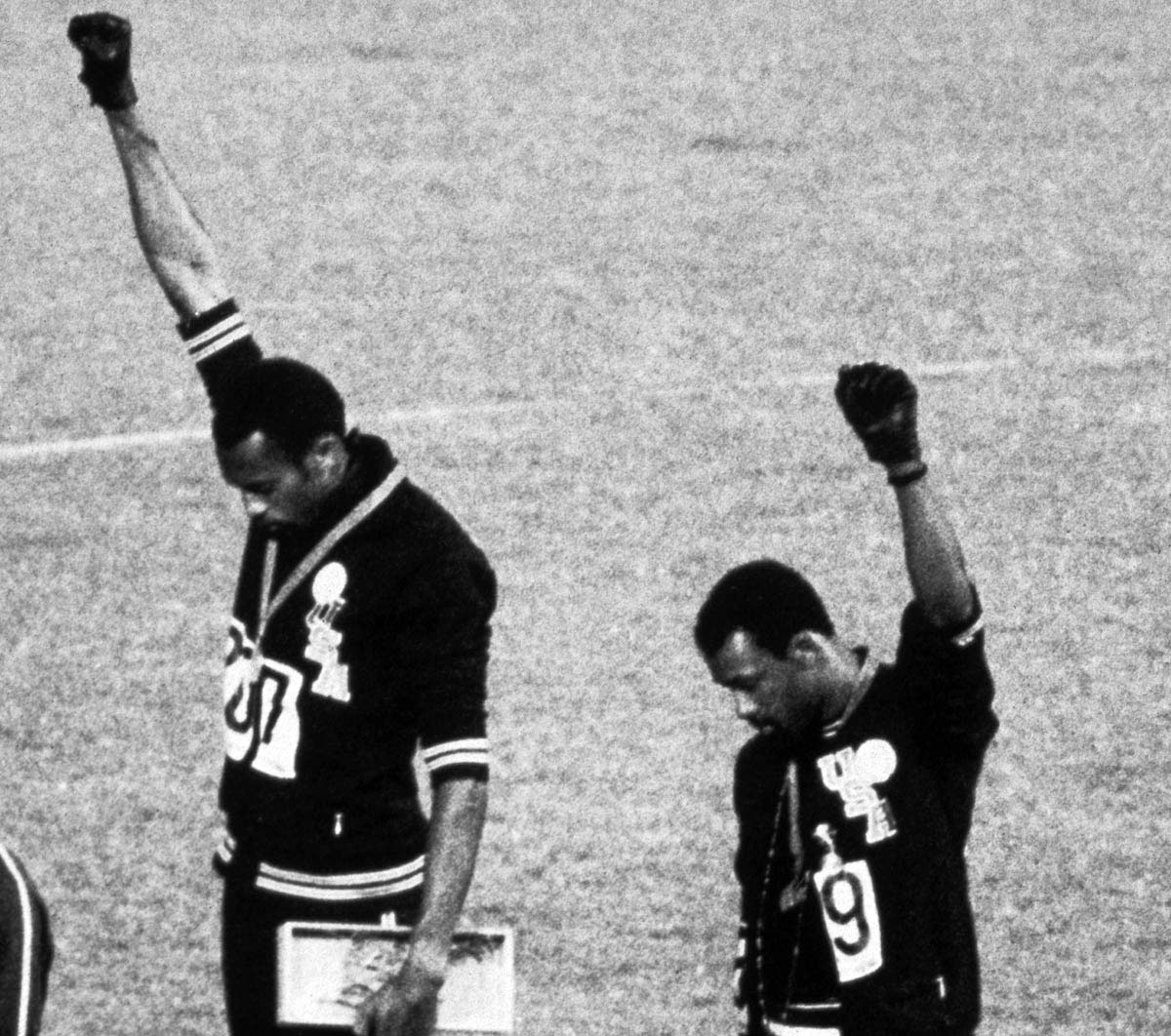 As <em>The Star-Spangled Banner</em> is played during the 1968 Mexico City Olympics, the American gold and bronze medalists in the 200-meter dash raise their fists in the Black Power salute. Outraged by this silent tribute to Black dignity and protest against racial discrimination in sports, the International Olympics Committee ejected Tommie Smith (center) and John Carlos (right) from the Olympic Village.