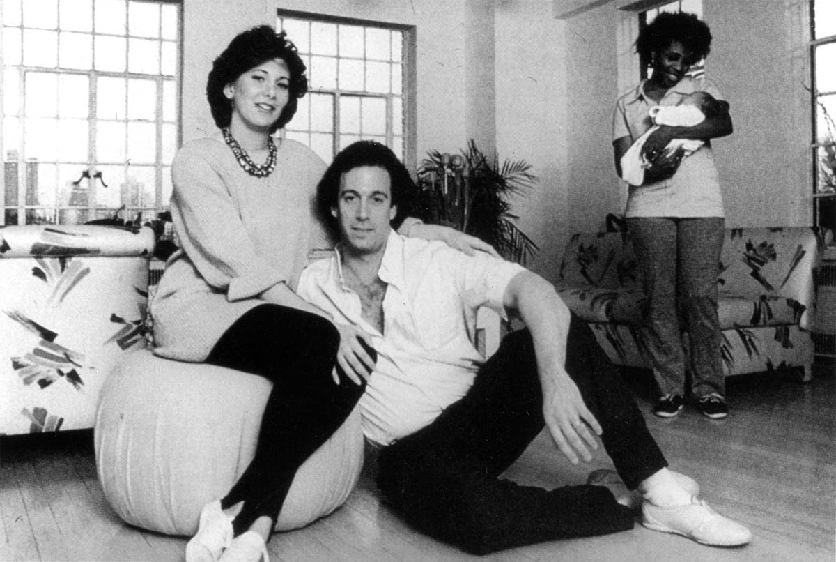 The ostentatious display of self and wealth became a hallmark of 1980s America. In this case, a young, upwardly mobile professional couple poses in their high-rise apartment for a magazine photograph—unself-consciously displaying the nanny as one of their possessions.