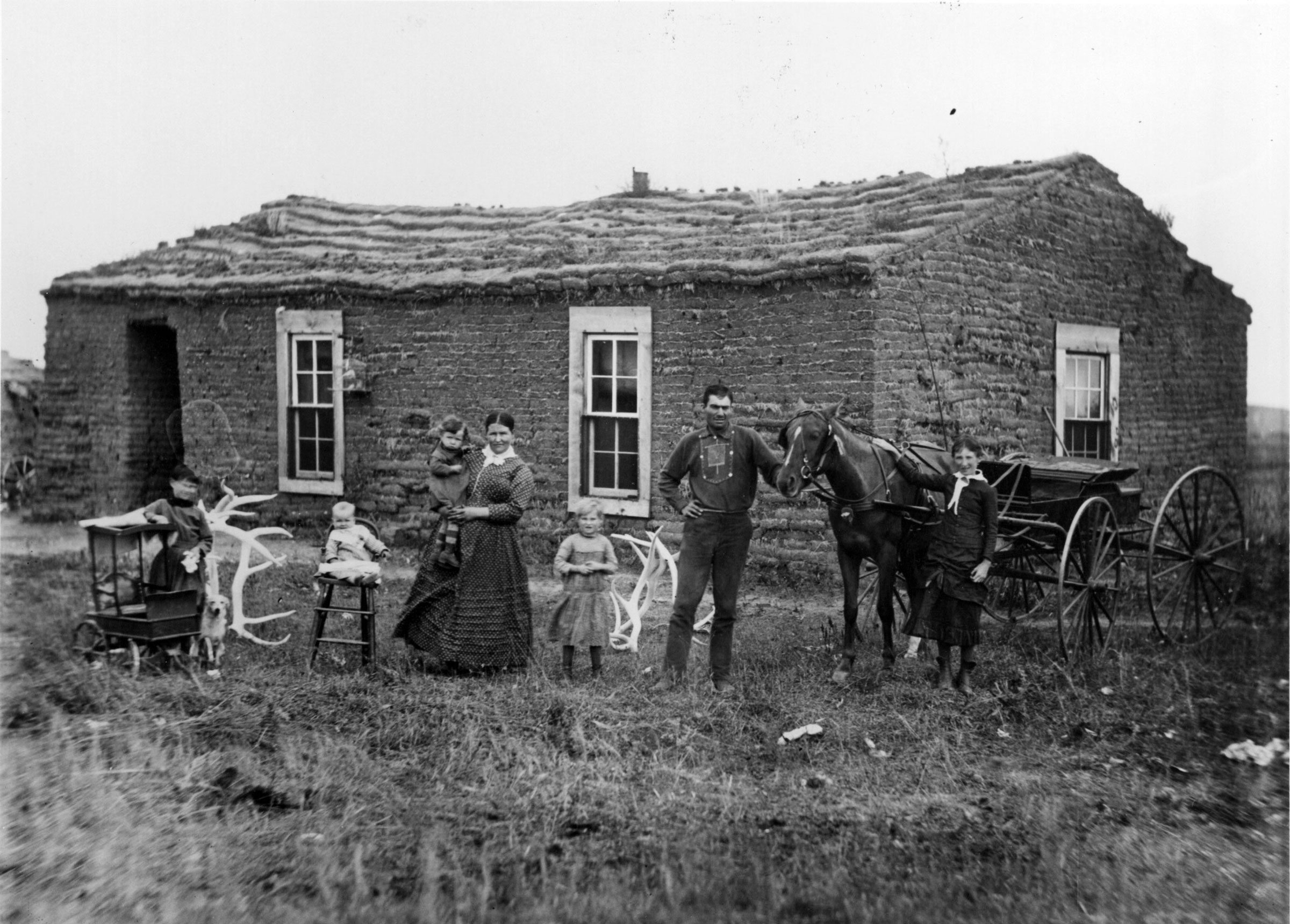 The Sommers family proudly poses for a photographer in front of their sod house in West Custer County, Nebraska, in 1888. One photographer recalled, “Whenever the traveling photographer came ’round, the sodbusters trotted out all of their possessions. The children were always outfitted in their Sunday best.” Families were eager to show friends and relatives back East that their new modest-looking homes were practical adaptations to prairie living and not evidence of poverty. Because cameras could not yet photograph dark interiors, settlers did their best to bring outside whatever prized possessions they owned.