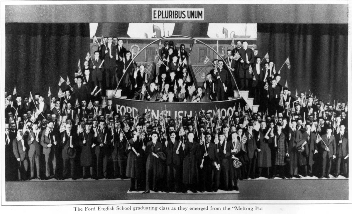 These 1916 graduates of the Ford English School are shown at the finale of commencement exercises. The graduation included a ritual of citizenship in which the graduates, wearing traditional national costumes, disembarked from an immigrant ship and disappeared into a gigantic melting pot (center of photo). Their teachers then vociferously stirred the pot with ladles, and the graduates finally emerged dressed in “American” clothes and waving flags.