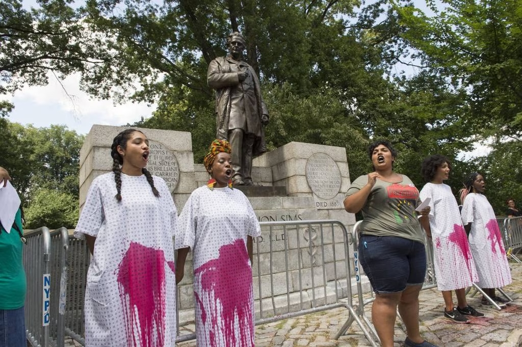 <em>This image shows protestors demanding that New York City remove a statue honoring J. Marion Sims. In the nineteenth century, Sims, a white doctor from Alabama, performed dozens of experimental gynecological surgeries on enslaved women without anesthesia. Sims also compelled enslaved women to assist him in his medical experimentation as well as serve as subjects of the experiments. A statue of Sims stood in New York’s Central Park, across from the New York Academy of Medicine, for over a century, showing the enduring esteem granted to Sims by his professional colleagues. After years of protests, in 2018 the statue was removed.</em>